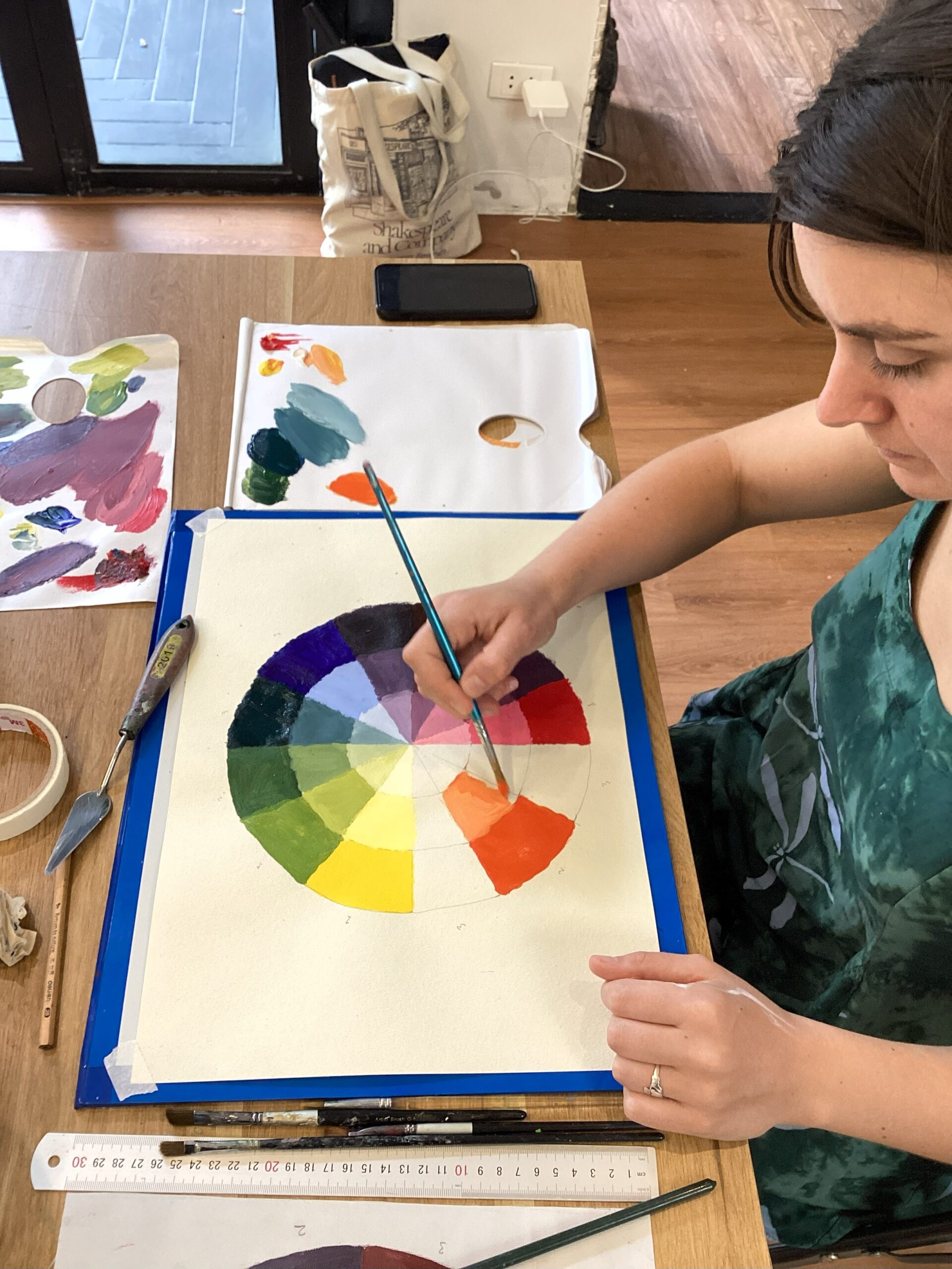 A woman painting a color wheel on a table inside an art studio in hanoi